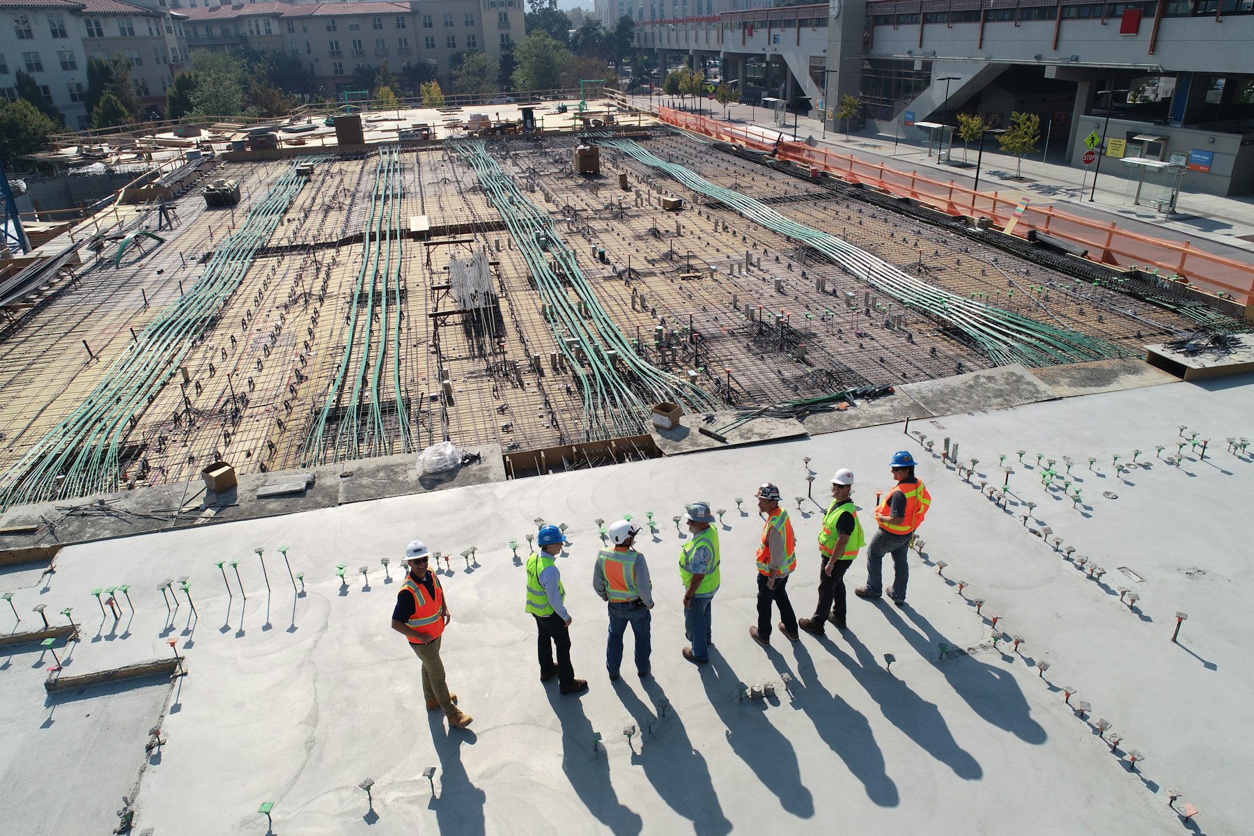 Cuadrilla de operarios con casco y chaleco reflectante recorriendo una obra en construcción
